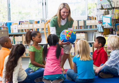 Kindergarten teacher and children looking at globe in library
